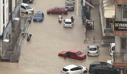 Yağmurda mahsur kalan motosikletli çareyi otomobilin üzerine çıkmakta buldu